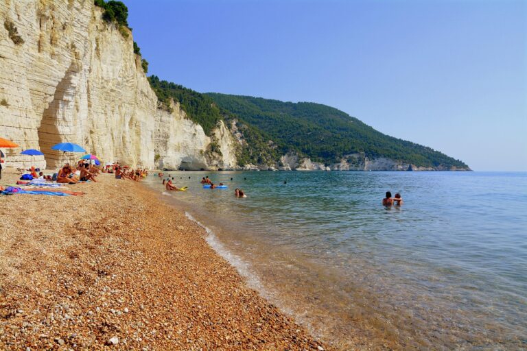 Spiaggia di Mezzavalle, con sabbia dorata e scogliere, vista panoramica mozzafiato e vegetazione rigogliosa.