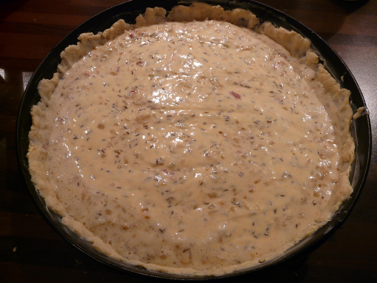 Torta salata con pasta bucherellata, pronta per la cottura "in bianco" su un piano di lavoro.