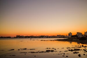 Tramonto mozzafiato sulla spiaggia di Punta della Suina, con colori caldi e onde che si infrangono.