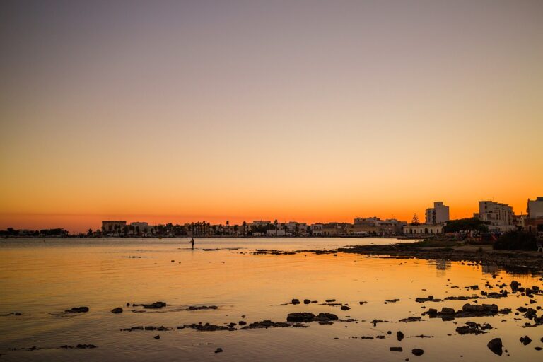 Tramonto mozzafiato sulla spiaggia di Punta della Suina, con colori caldi e onde che si infrangono.