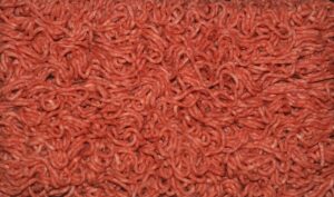 Carne macinata in vaschetta con colore grigio sul fondo, avviso per la freschezza del prodotto.